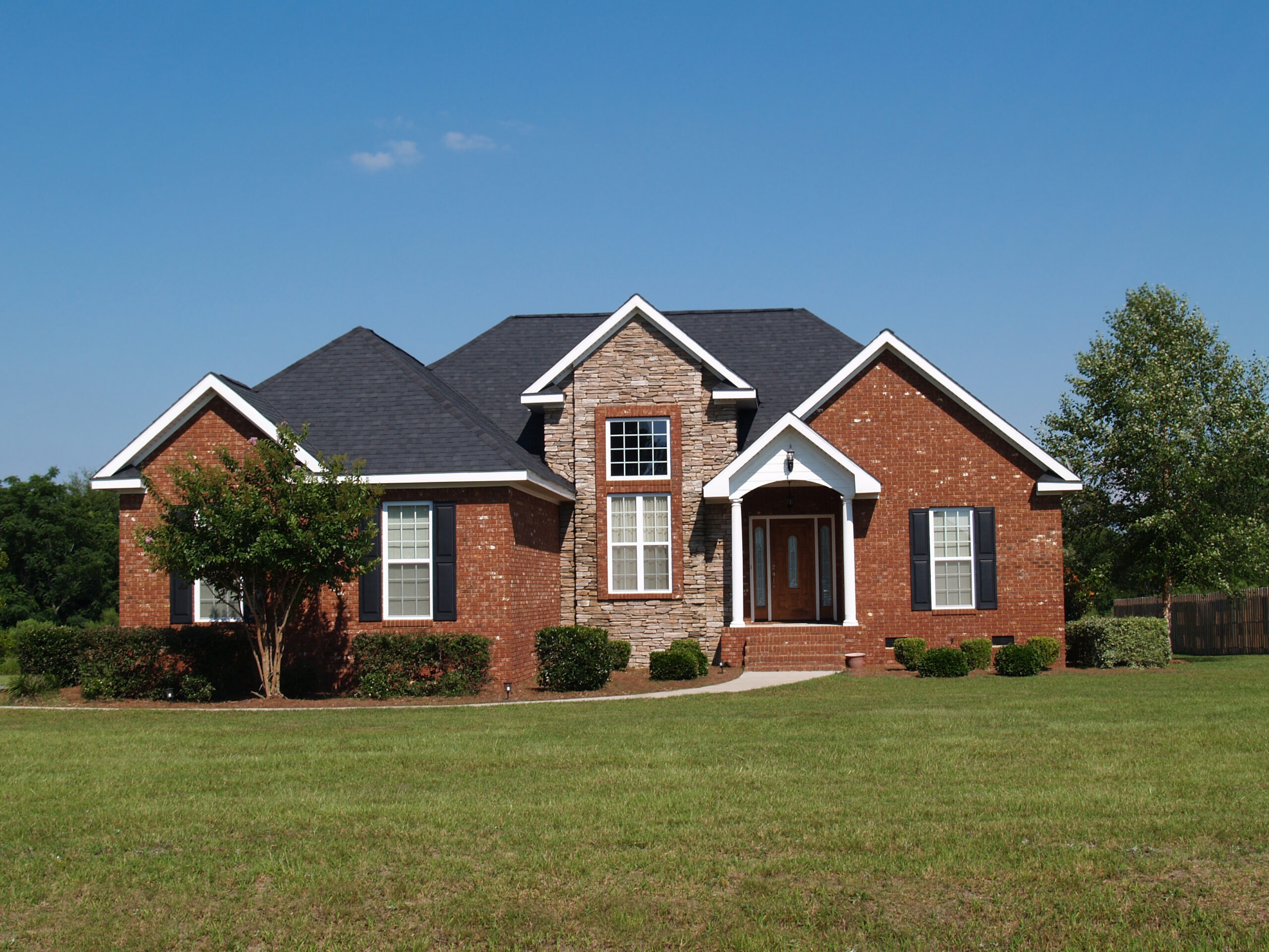 A charming brick house with black roof, stone accent